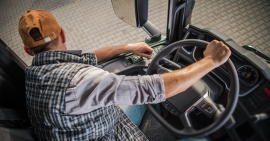 top view of a driver sitting in the front seat of a large truck looking out the window towards the ground